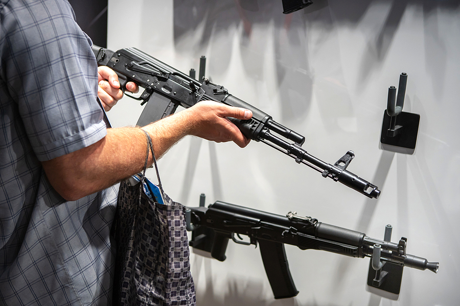 A Man In Civilian Clothes Examines Samples Of Firearms.