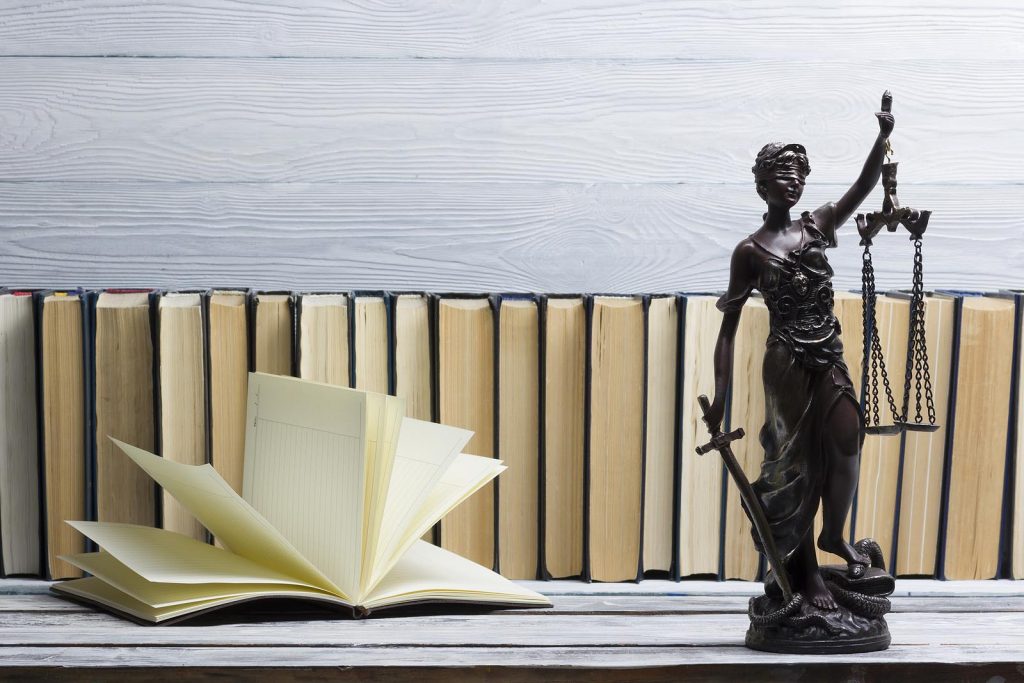 Open law book with a wooden judges gavel on table in a courtroom.